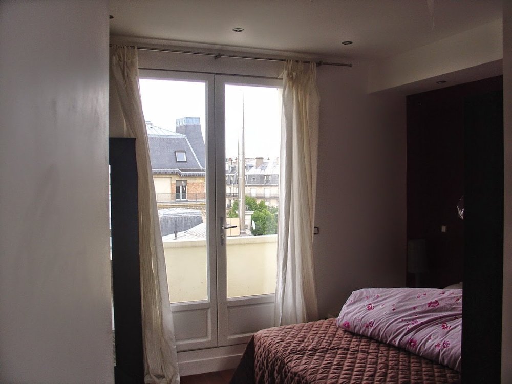 A bedroom with a quilted bedspread and glazed balcony doors.
