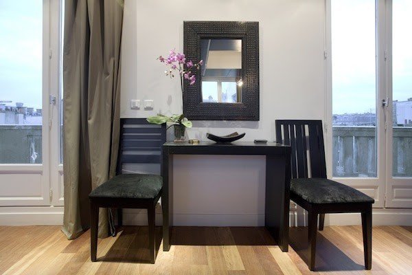 A writing table and two chairs between balcony doors.